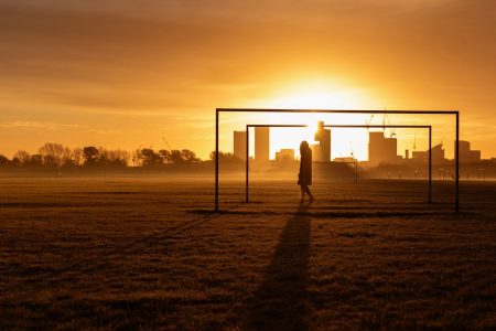 Business traveller walking at sunrise, framed by architecture, representing preparation, awareness, and knowledge as confidence tools